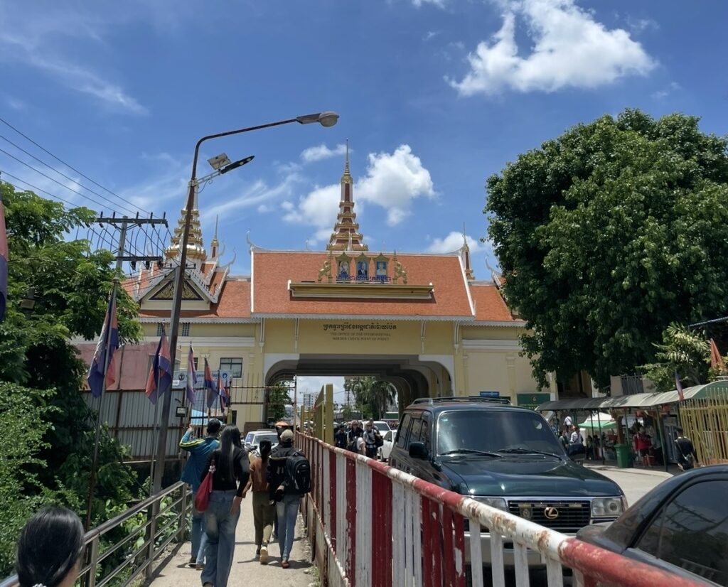 タイとカンボジアの国境ゲート。クメール様式の建築が並ぶ入国ポイントで、歩行者と車が行き交う陸路国境の様子。アランヤプラテートからポイペトへ向かう旅行者が多く利用する越境ルート。