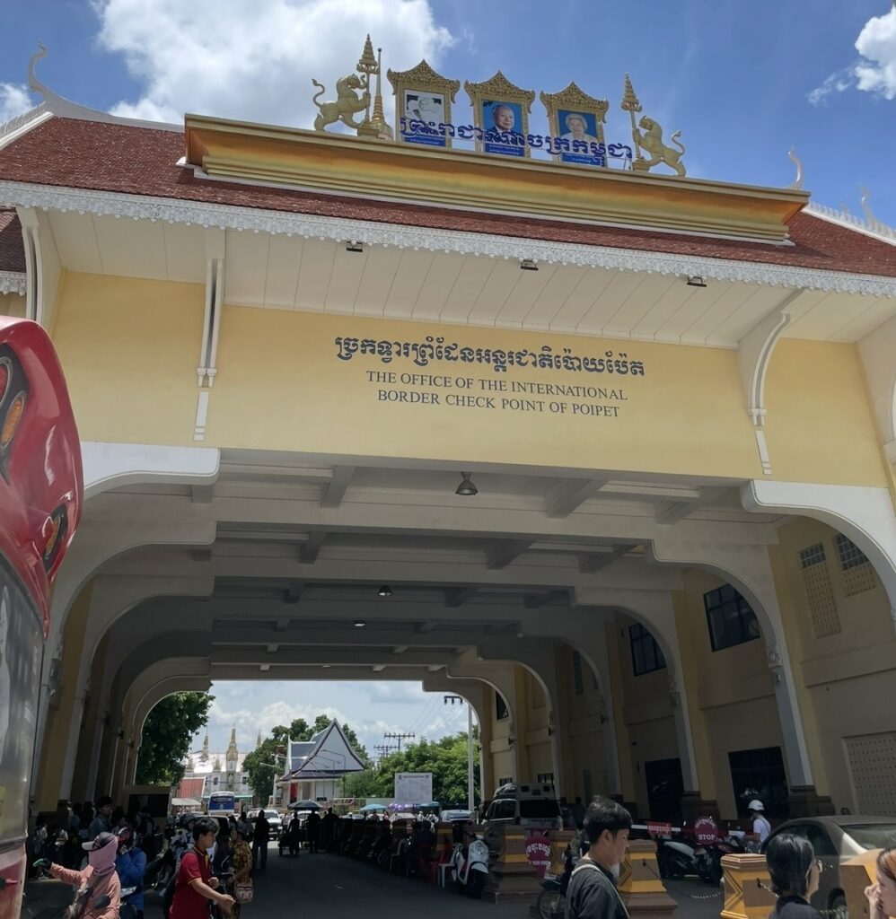 カンボジア側ポイペト国境の入国チェックポイント。クメール様式の装飾が施された建物の下で旅行者が行き交い、タイから陸路で入国する際によく利用される主要な国境ゲート。