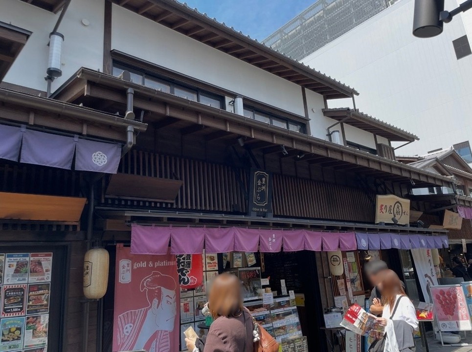 千客萬來內『金ぷら』店面，以江戶風格建築與紫色門簾呈現的熱鬧街景。