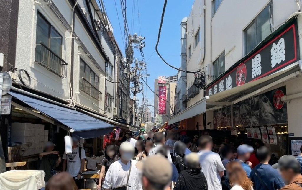 築地場外市場的最後一張街景，狹窄巷道兩側是餐飲與食材店舖，人潮絡繹不絕的熱鬧氛圍。