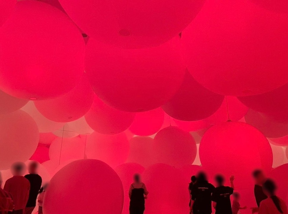 teamLab Planets 豊洲の巨大な光のバルーンが並ぶインスタレーション。赤やピンクの光に包まれた球体の間を来館者が歩き、没入型デジタルアートを体験できるエリア。