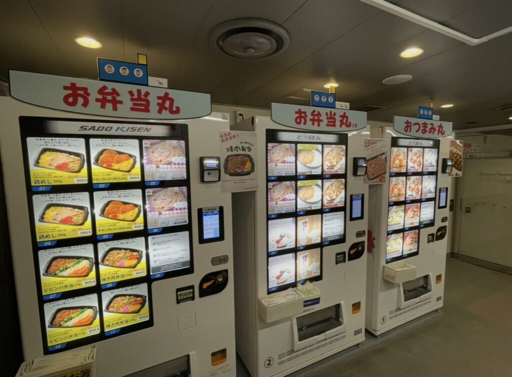 渡輪船內設置的便當自動販賣機。各式便當與輕食的選項排列其中，讓乘客在航行途中也能購買餐點。