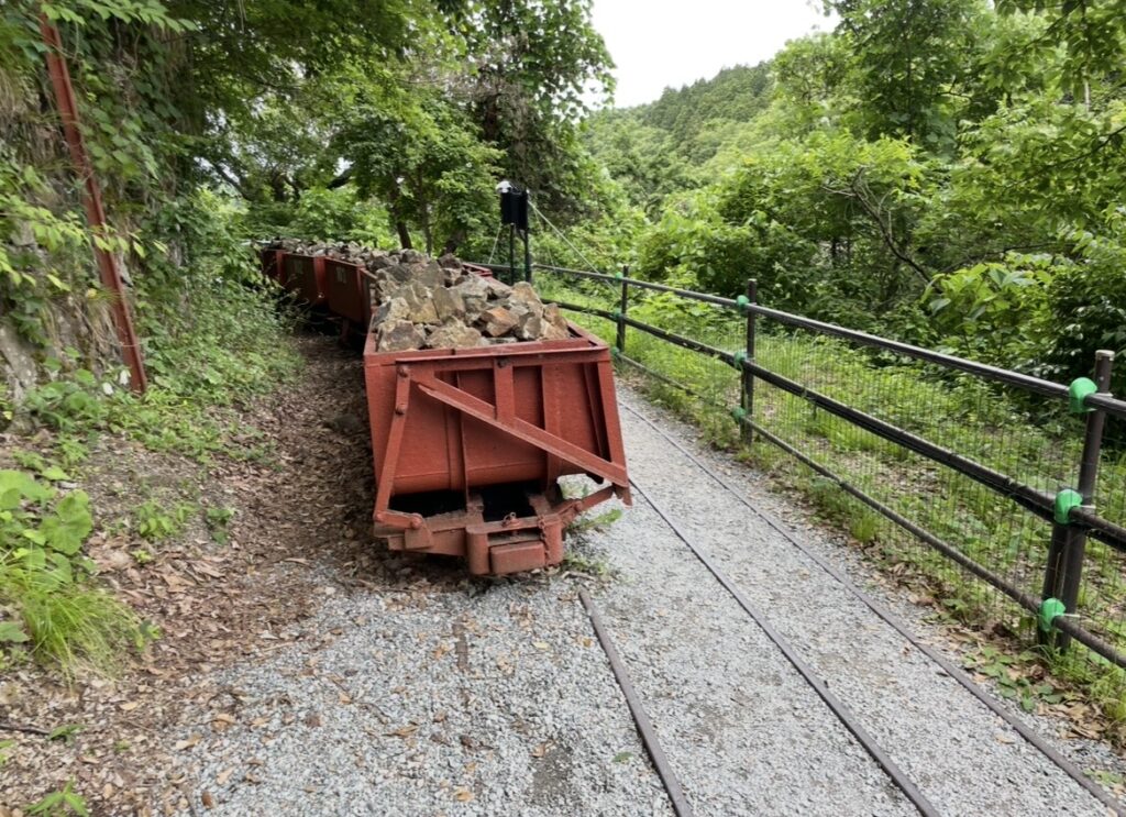 佐渡金山に残るトロッコの遺構。細い軌道上に鉱石を積んだ台車が並び、当時の運搬作業の様子を伝える歴史的設備。