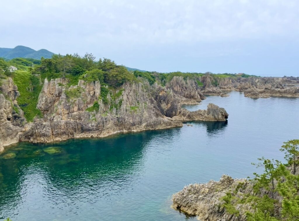 尖閣湾の荒々しい岩肌と透明度の高い海が広がる絶景の写真。断崖と入り江が織りなす独特の地形が美しく映し出されている。