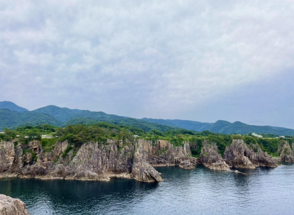 尖閣湾の荒々しい岩肌と静かな入り江が広がる景観の写真。断崖と透明度の高い海がつくり出す絶景が印象的に映し出されている。