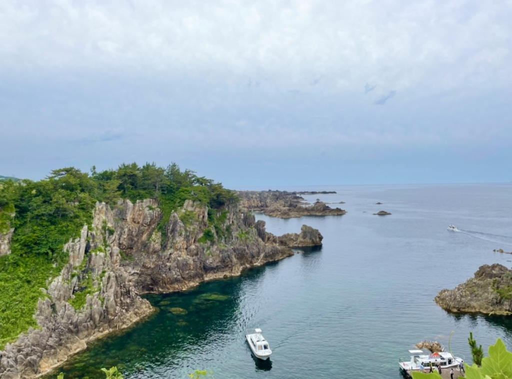 尖閣灣的壯麗斷崖與清澈海水為背景，遊覽船靜靜停泊在海面上的景觀照片，呈現從海上欣賞的震撼美景。