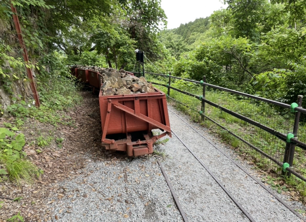 Remains of trolley tracks at the Sado Gold Mine. Small ore carts line the narrow rails, illustrating how excavated rock was transported during the mine’s operation.