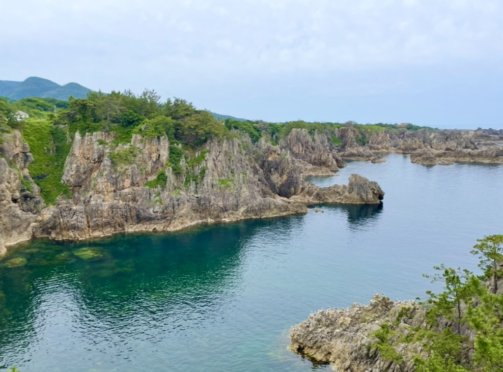 Scenic view of Senkaku Bay featuring rugged rock formations and crystal‑clear blue waters. The dramatic cliffs and intricate inlets highlight the area’s uniquely shaped coastline.