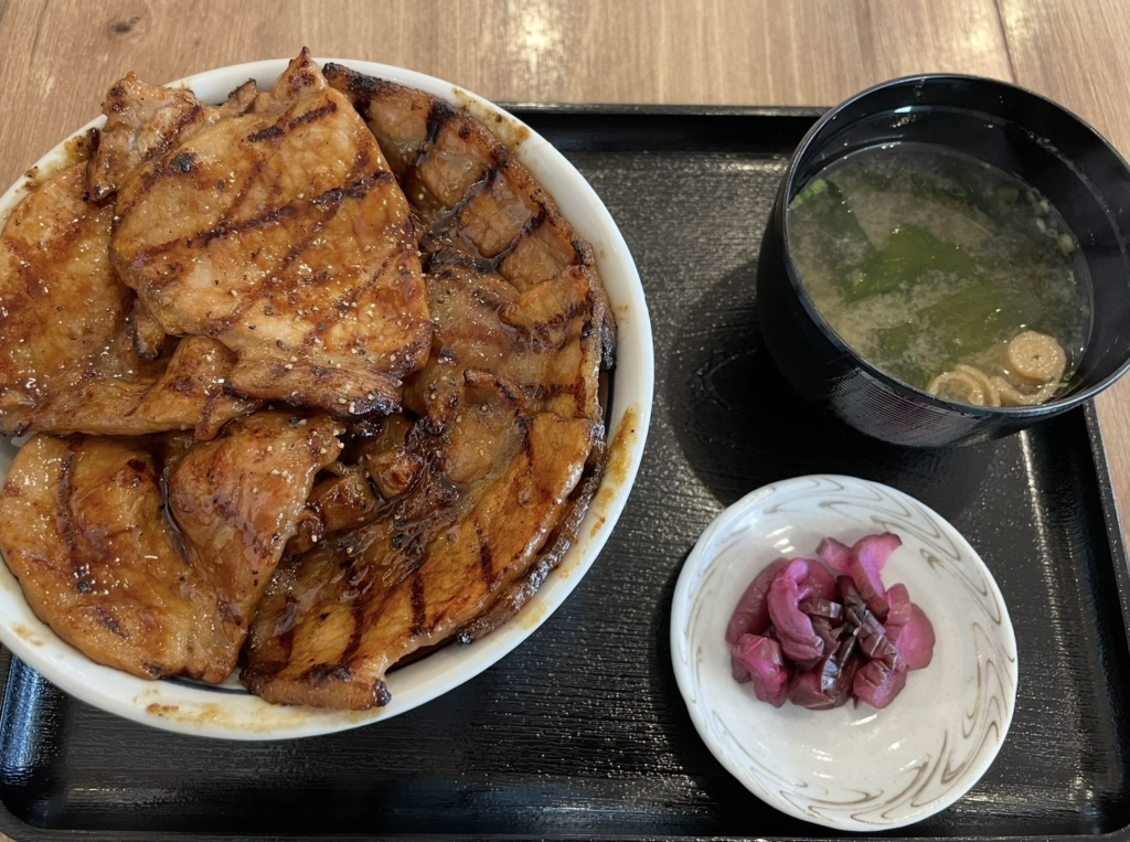 Charcoal‑grilled slices of pork loin layered over rice, coated with a glossy sweet‑savory sauce.
Served as a set with miso soup and pickles, creating a classic and satisfying butadon presentation.