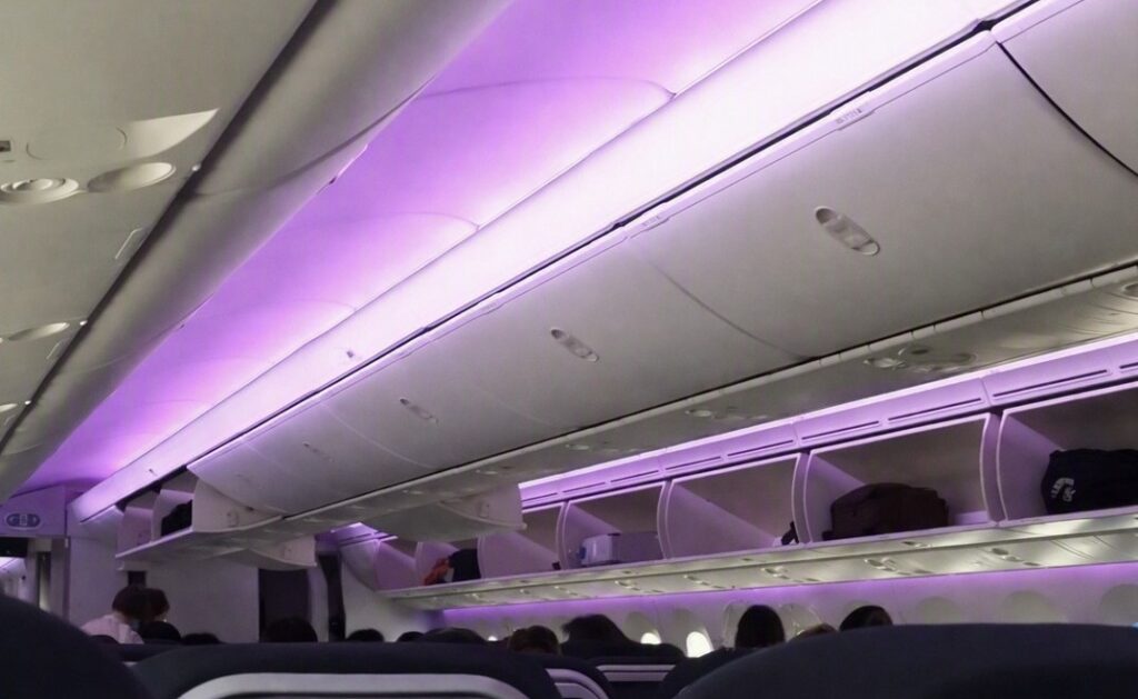 ニュージーランド航空の機内を撮影した写真。紫色の照明が印象的なキャビンで、快適な長距離フライトの雰囲気を伝える。