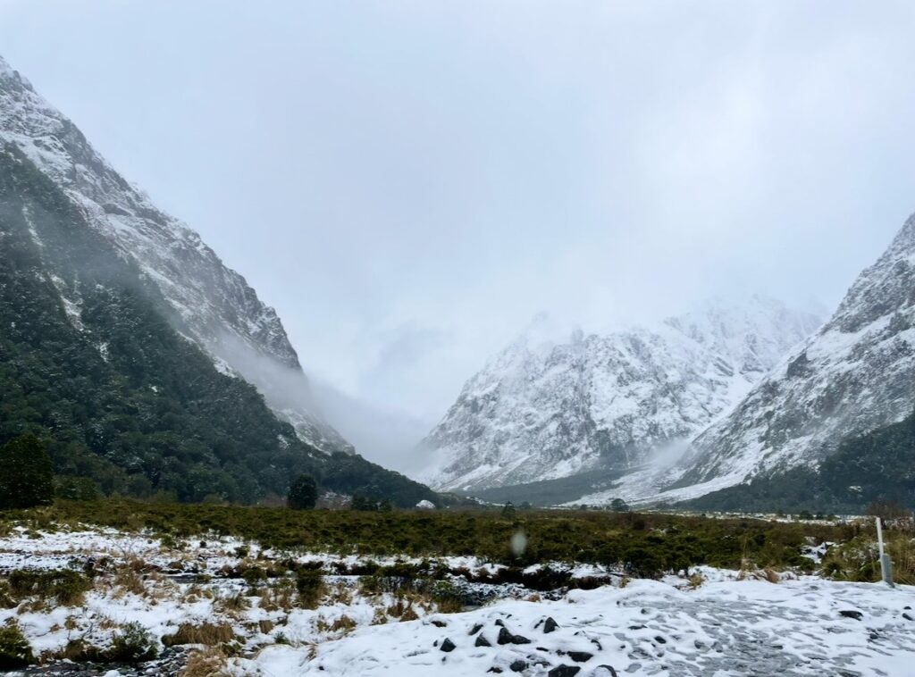 ミルフォードサウンドへ向かう道中で見える雪化粧の山々と霧に包まれた冬の谷間