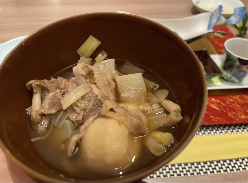 ほほえみの宿 滝の湯で提供される山形名物・芋煮。牛肉、里芋、ねぎ、きのこを合わせた郷土料理が椀に盛られた写真。