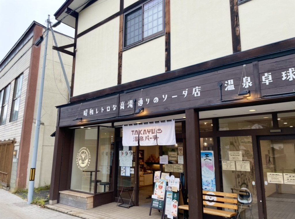 藏王溫泉的 TAKAYU Parlor 外觀。
木造的懷舊店面掛著寫有「溫泉 Parlor」的暖簾，昭和風招牌排列在門前。
透過玻璃可看到店內的吧台與菜單，是高湯通上深受歡迎的咖啡甜點店。