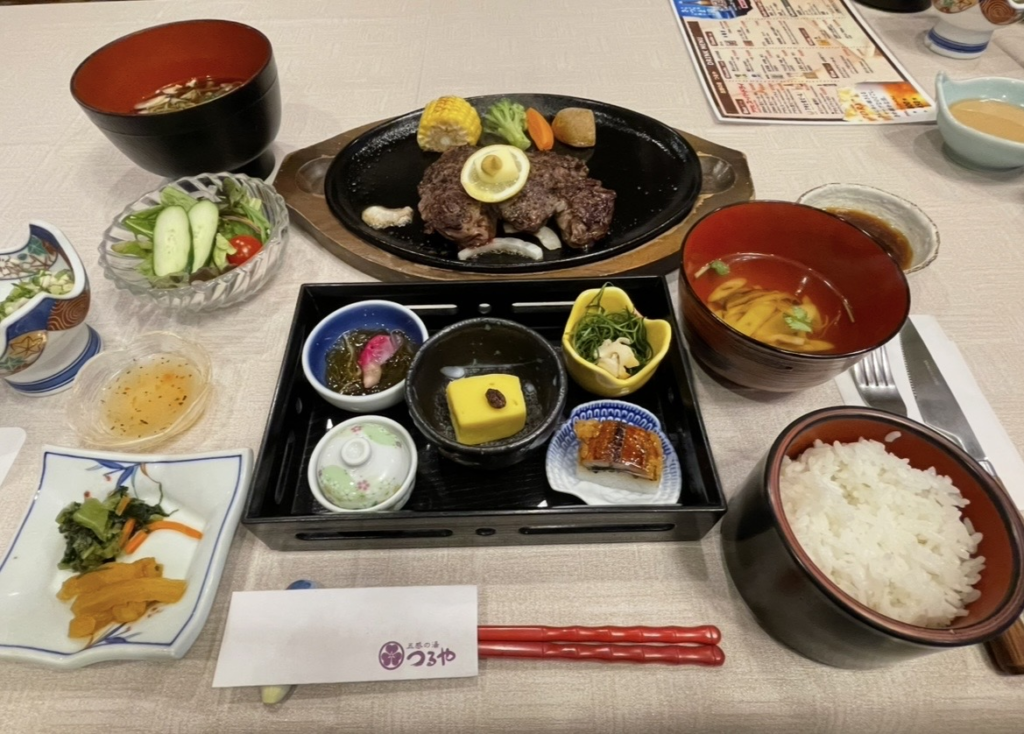 A Japanese dinner set featuring a Zao Beef steak as the centerpiece, accompanied by seasonal Yamagata dishes such as grilled items, simmered dishes, small side bowls, miso soup, and white rice. The beautifully arranged presentation reflects the refined dining style unique to traditional ryokan cuisine.