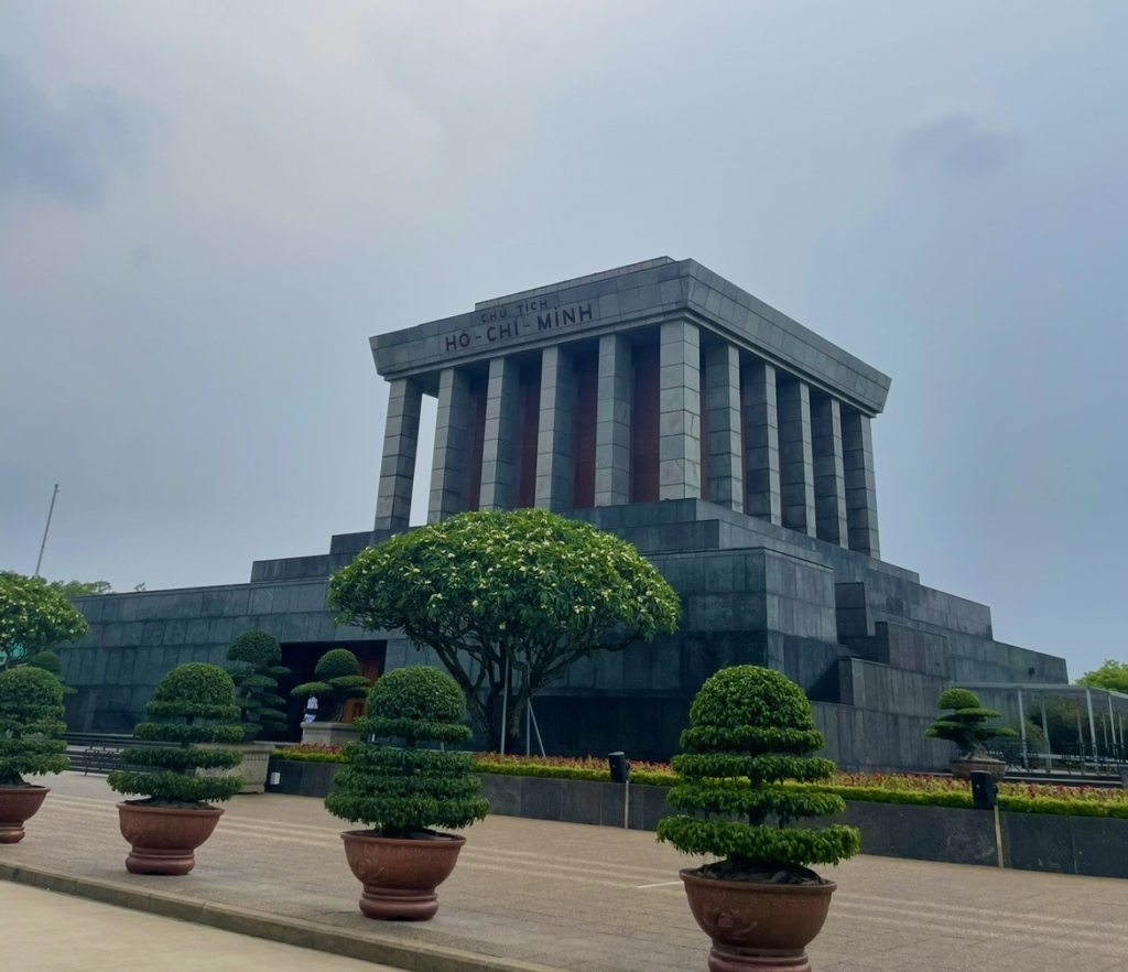 Quiet plaza at Hanoi’s Ho Chi Minh Mausoleum with heavy stone architecture and neatly arranged greenery