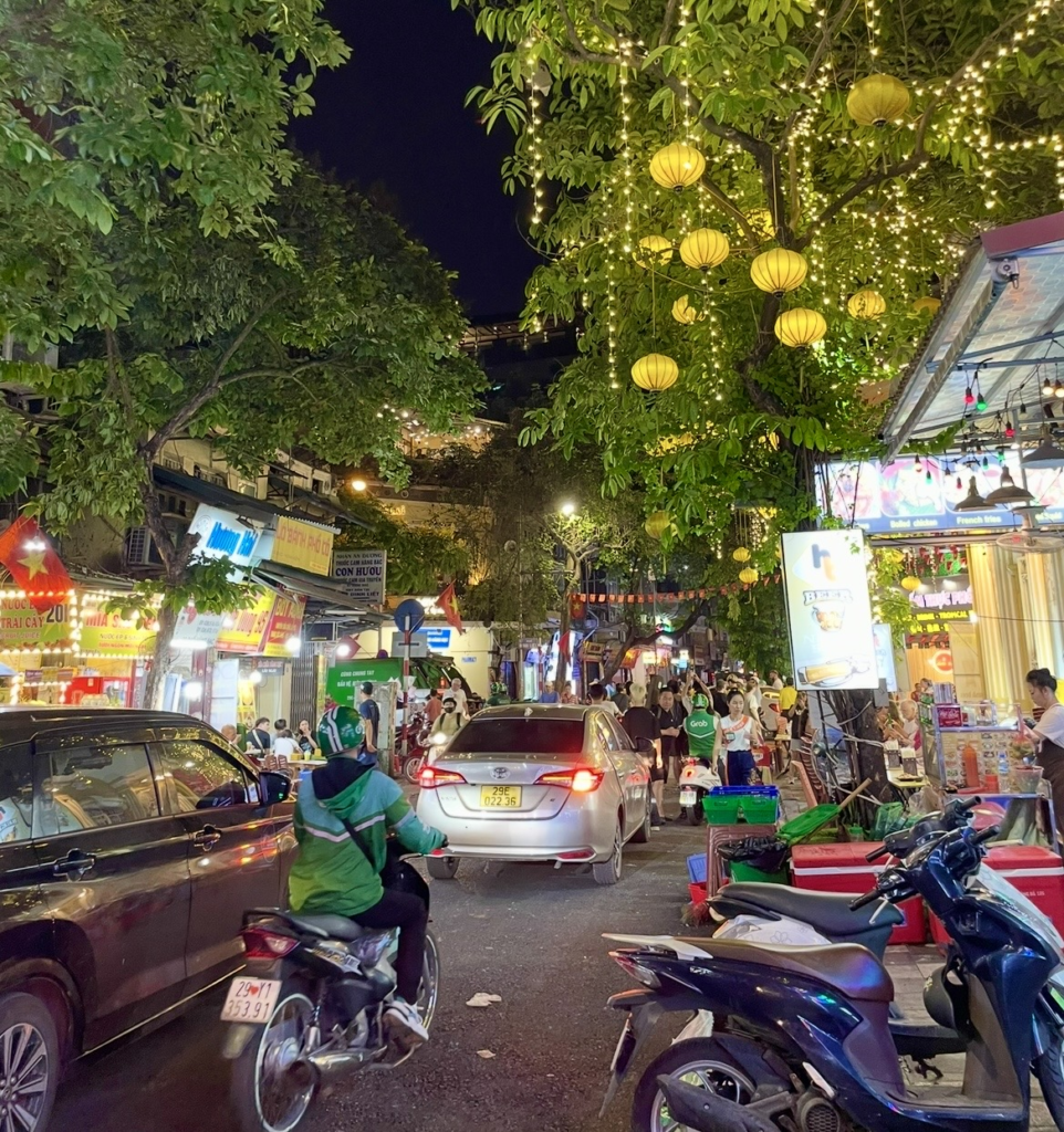 河內舊城區夜晚,成排的黃色燈籠照亮街道,攤販、汽車與機車燈光交織的熱鬧景象