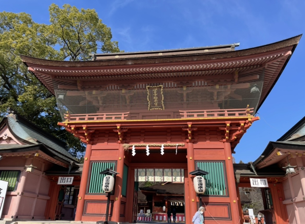 富士山本宮淺間大社的樓門,鮮紅的門身與精緻木構造十分醒目,兩側掛有傳統燈籠,後方可見拜殿的建築。