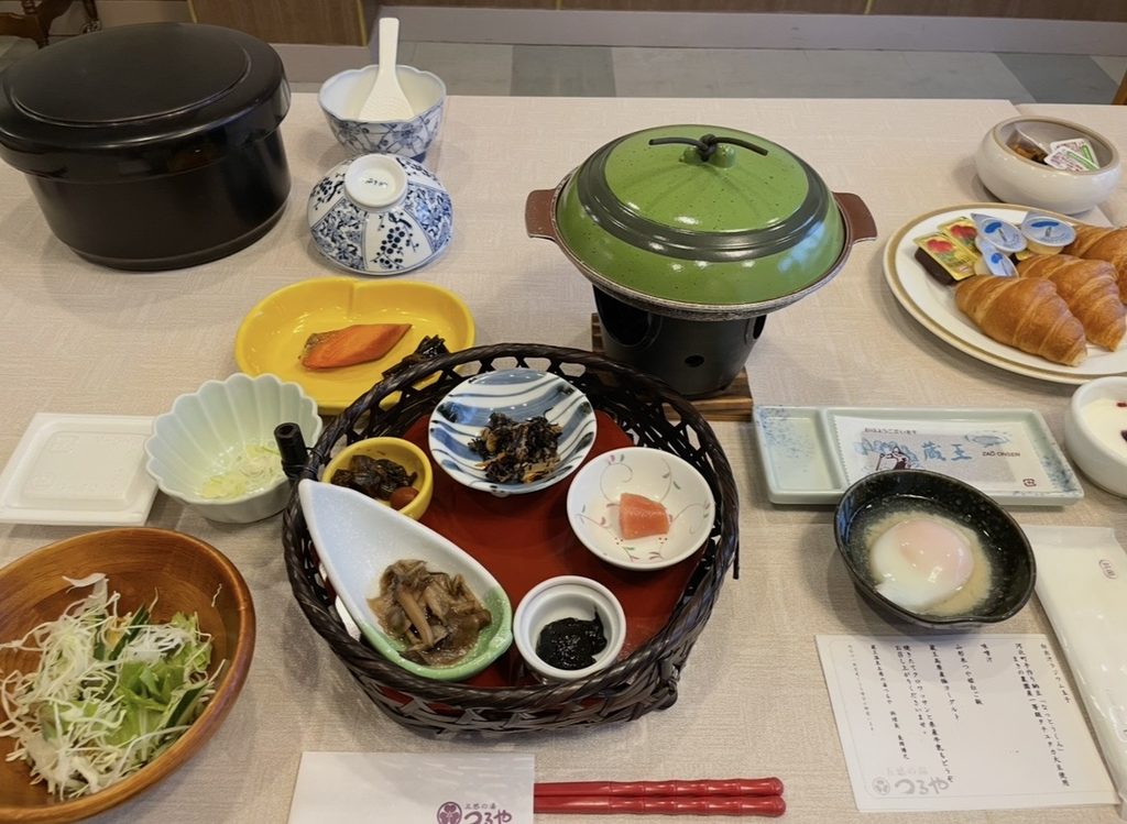 五感の湯つるやの朝食。焼き鮭や和惣菜の小鉢、温泉卵、味噌汁、クロワッサンなどが並ぶ和食メインの朝食膳で、蔵王温泉の旅館らしい丁寧な食事が楽しめる。