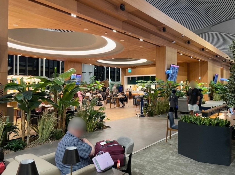 A lounge area inside Istanbul Airport featuring warm wooden interiors. The calm space shows travelers relaxing as they wait for their departures, creating a cozy and tranquil atmosphere.