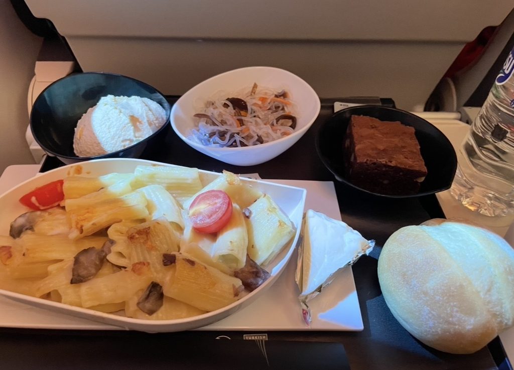 ターキッシュエアラインズの機内食として提供されたリガトーニ。チーズがとろけるパスタに前菜やデザートが添えられ、長距離フライトでも満足感のある食事が楽しめる内容になっている。