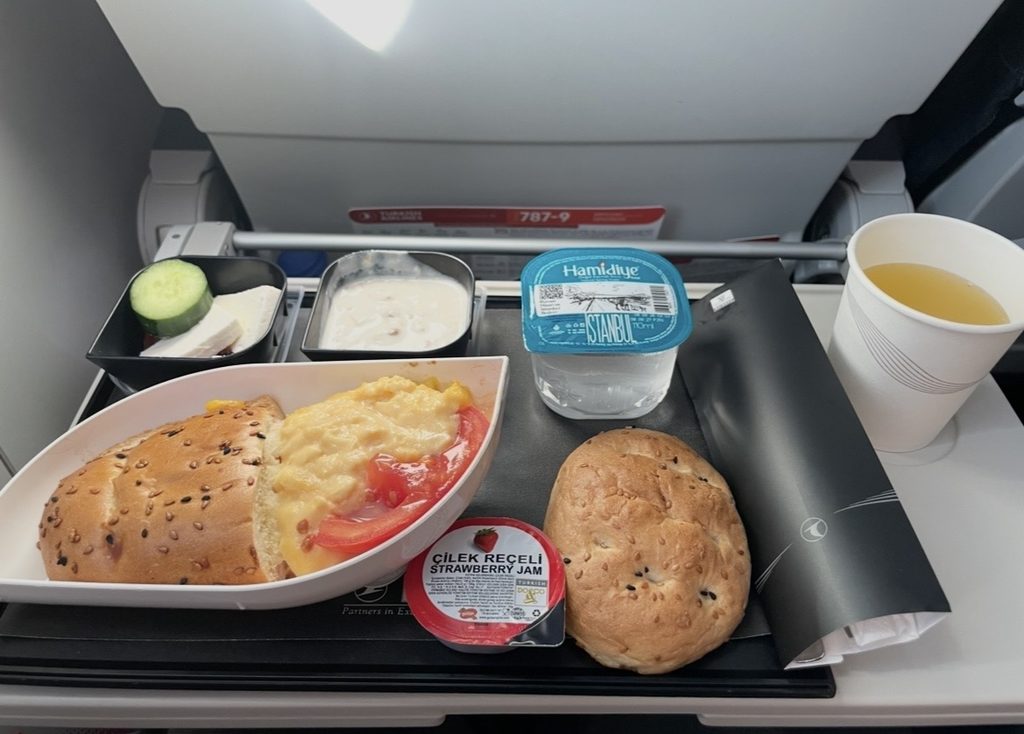 イスタンブール発マルタ行きのターキッシュエアラインズで提供された朝食。スクランブルエッグにトマト、チーズやヨーグルト、パン、ジュースが並び、短距離欧州路線らしい軽めの朝食セットが楽しめる内容になっている。