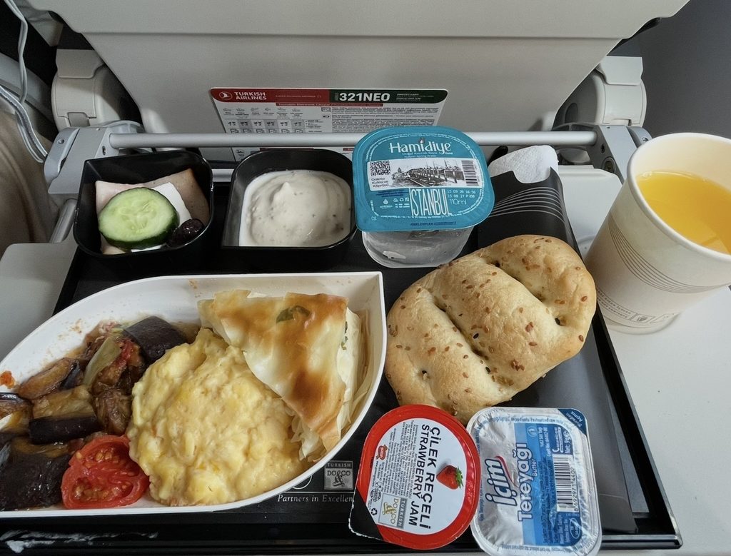 バーリ発イスタンブール行きのターキッシュエアラインズで提供された朝食。スクランブルエッグに焼き野菜、チーズやヨーグルト、パン、ジュースが並び、欧州域内路線らしいバランスの良い朝食セットが楽しめる内容になっている。