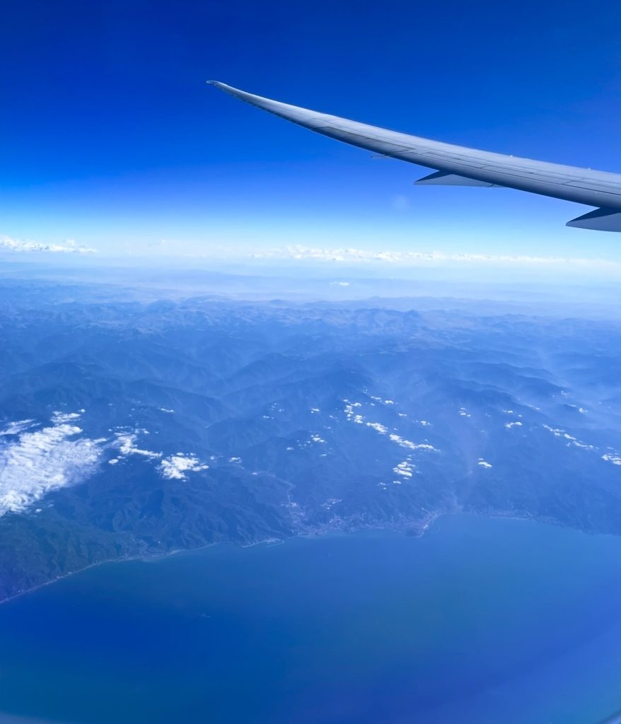 黒海沿岸の山並みを上空から望む機窓風景。海岸線と緑の山地が広がり、翼越しに雄大な地形のコントラストが伝わる。