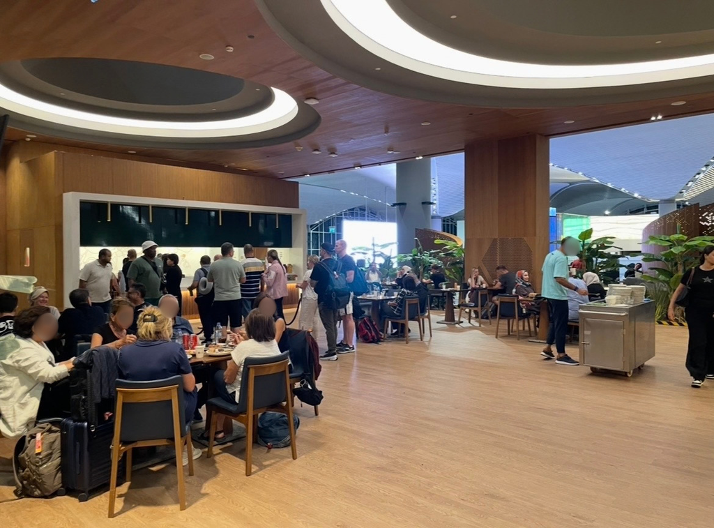 The dining area of the IGA Lounge at Istanbul Airport, a spacious setting with wood‑tone flooring and soft lighting where travelers enjoy meals and relaxation in a calm lounge atmosphere.