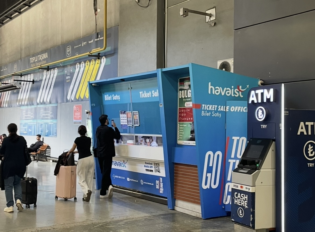The Havaist ticket counter at Istanbul Airport, with travelers passing in front of the blue ticket booth.