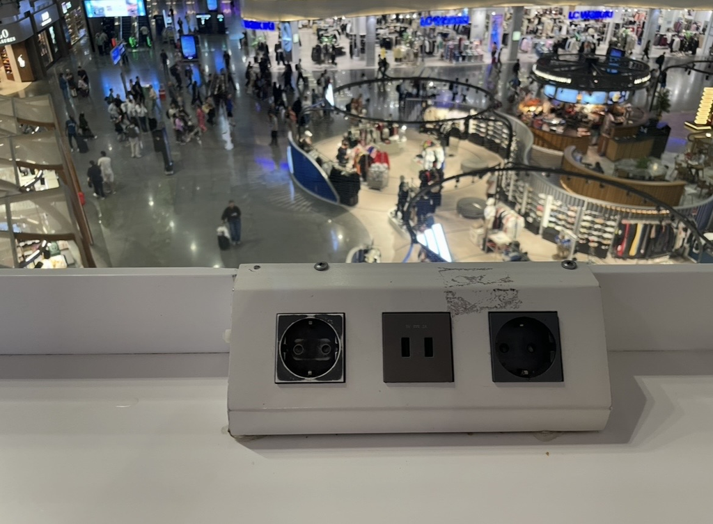 A power outlet located overlooking the food court at Istanbul Airport, equipped with both European‑style and universal sockets.
