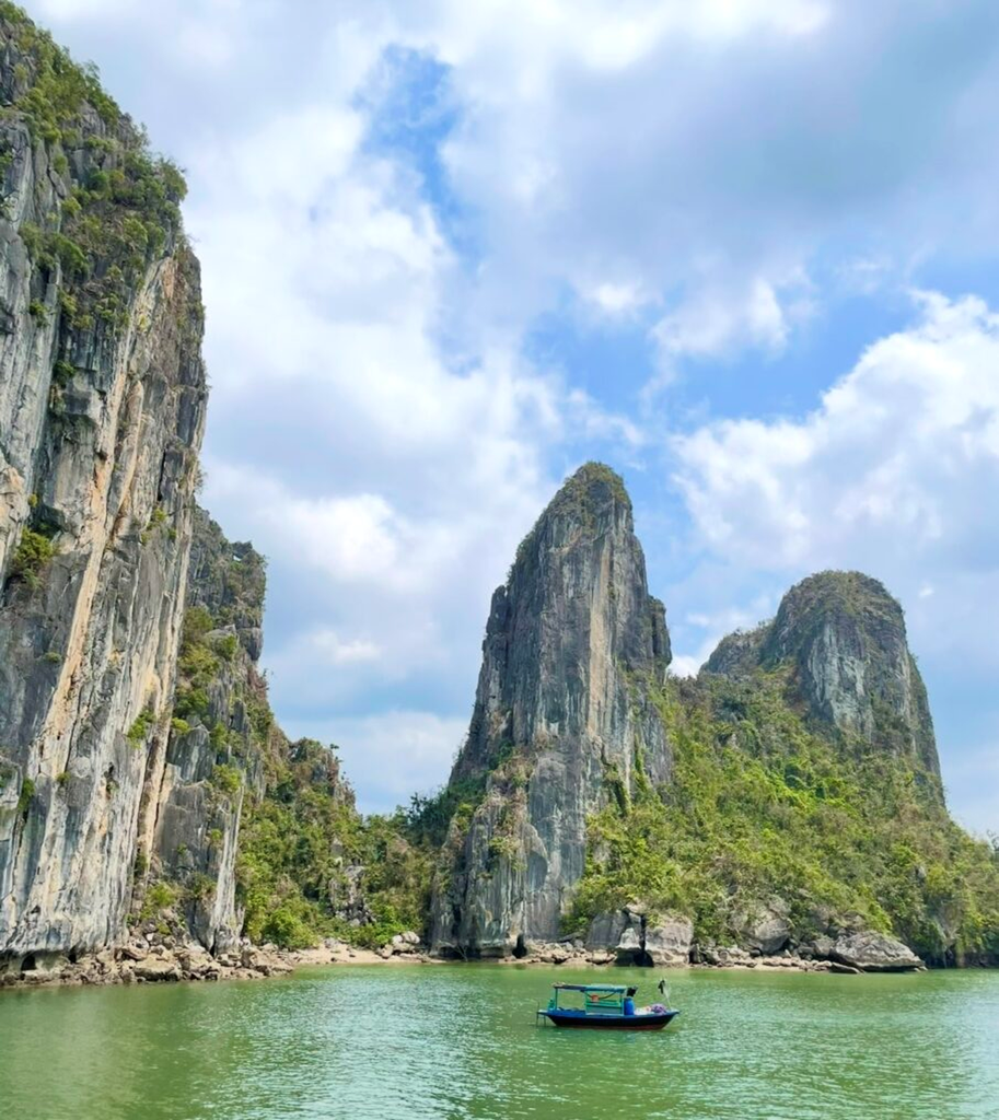 近距離欣賞下龍灣的石灰岩峭壁，覆滿綠意，平靜海面上漂浮著小船，呈現下龍灣雄偉而寧靜的景色。