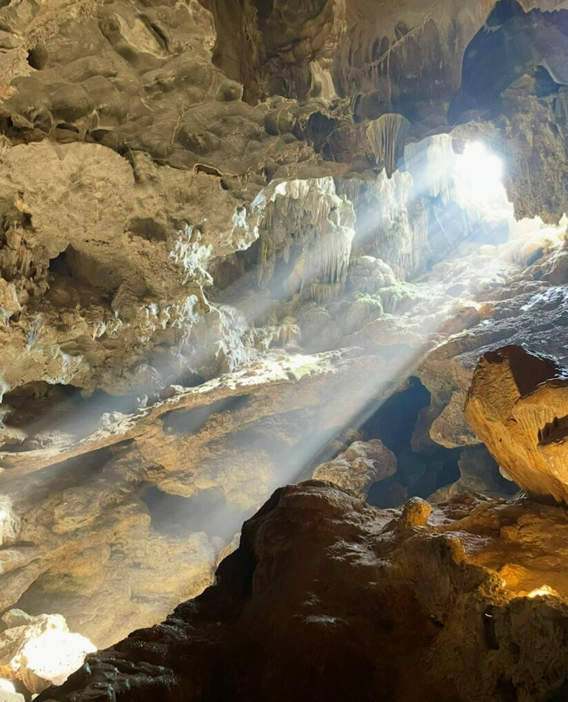日光照進下龍灣的驚訝洞，映亮岩壁與鐘乳石，在寬廣的洞窟中呈現出神秘又震撼的光影景致。