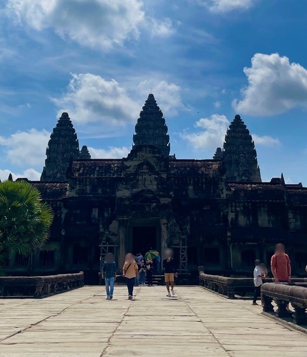 從正面仰望的吳哥窟（Angkor Wat）中央神廟，石板參道與逆光下矗立的三座高塔。