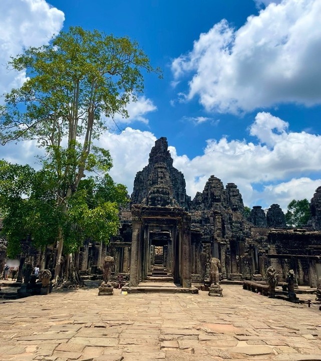 巴戎寺（Bayon Temple）的正面入口與石造門郭，大樹與藍天白雲環繞的神廟正面全景。