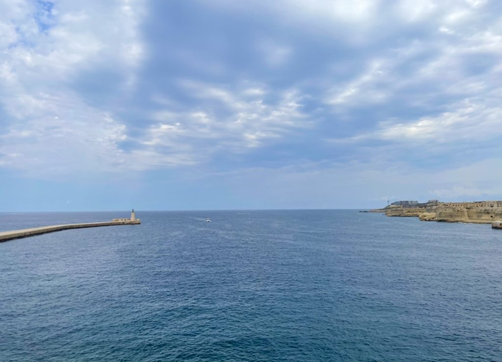 聖エルモ砦から望む地中海。防波堤と灯台が伸びる穏やかな海と、岸壁に残る要塞の風景が広がる静かな展望スポット。