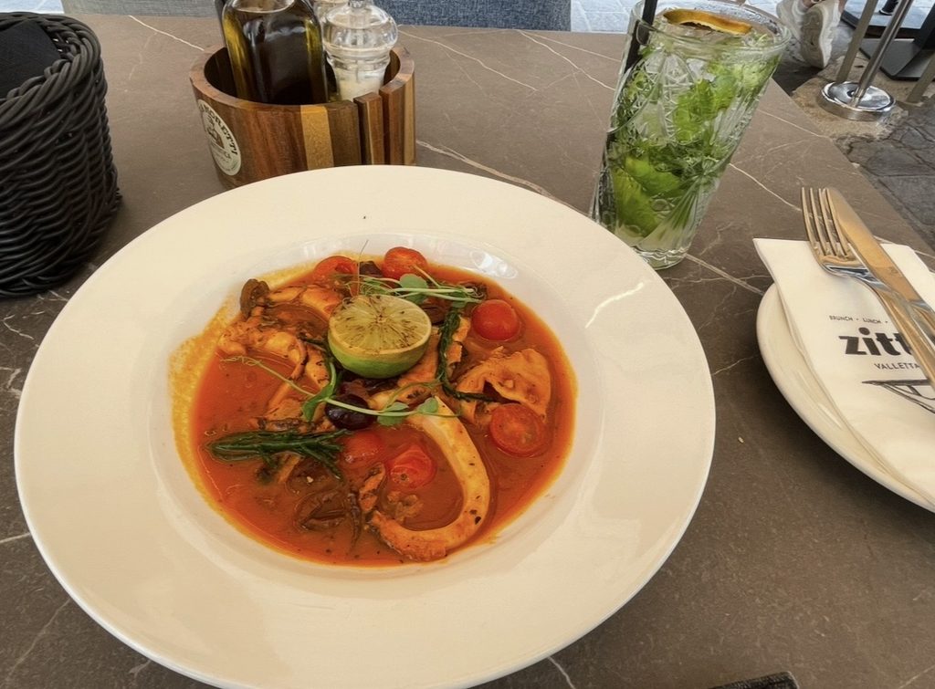 バレッタのストリートテラスで味わうシーフード料理。ライムとハーブが彩る一皿と爽やかなドリンクが、石造りの街並みに映える食の風景。