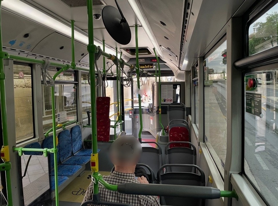 マルタの路線バスの車内後方から撮影した、前方の通路や左右の青色と赤色の座席シート、つり革が並ぶ様子。