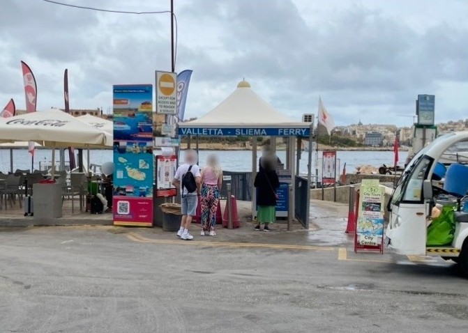 マルタの海辺に設置された、「VALLETTA - SLIEMA FERRY」の文字と白いテント屋根が目印のフェリー券売所と乗船ゲートの風景。