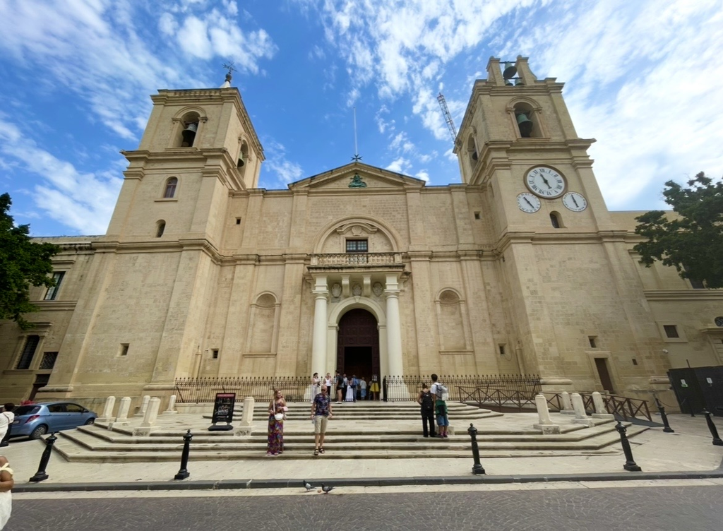 St. John’s Co‑Cathedral in Valletta, featuring a modest stone exterior with minimal ornamentation. The symmetrical bell towers and imposing entrance highlight the building’s historic architectural presence.