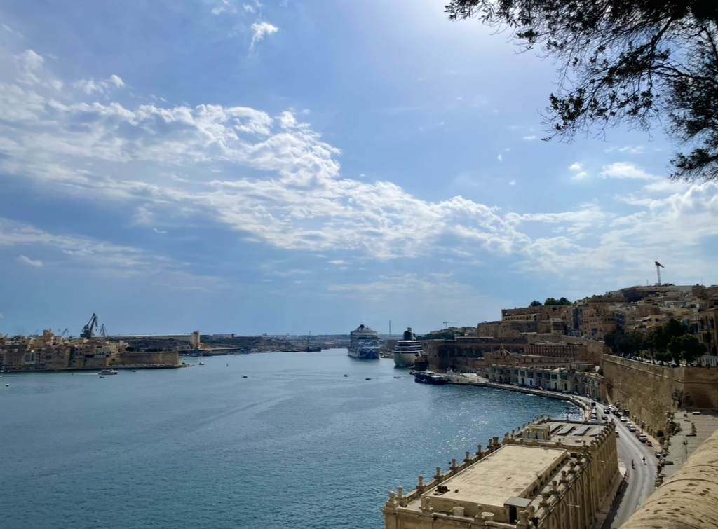 A harbor view from the Lower Barrakka Gardens, where historic stone buildings and moored ships create a classic Valletta scene blending sea and fortifications.