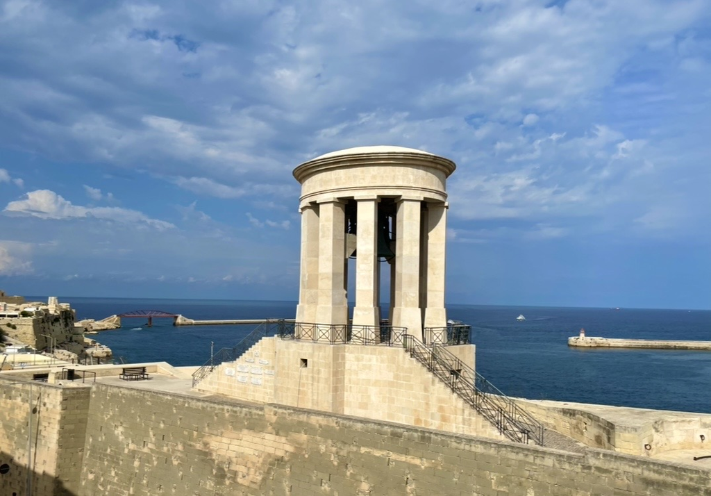 The Siege Bell War Memorial in Valletta, a circular colonnaded bell tower standing on the seafront bastion. Overlooking the Grand Harbour, it serves as a quiet monument honoring those who died during the Siege of Malta.