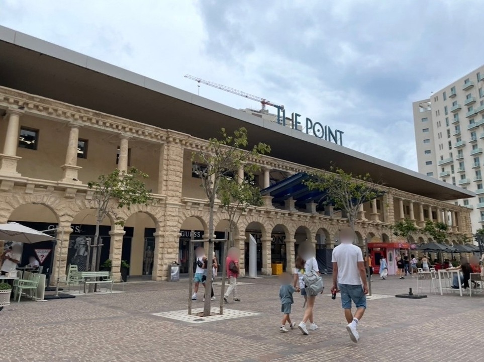 The Point shopping mall in Sliema, where stone architecture frames rows of brand stores, and terrace seating opens onto a stylish seaside urban atmosphere.
